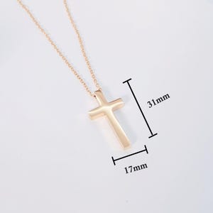 May include: A gold-tone cross pendant necklace with a simple, minimalist design. The pendant measures 1.22 inches in length and 0.67 inches in width.