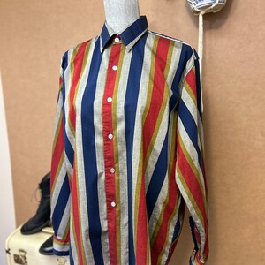 Peut inclure: Une chemise &agrave; manches longues &agrave; boutons avec des rayures diagonales en rouge, bleu, or et gris.
