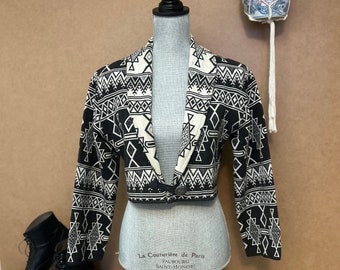 May include: A black and white cropped jacket with a geometric pattern. The jacket has a collar and a button closure. The label on the jacket reads "La Couturiere de Paris, Faubourg Saint-Honore".