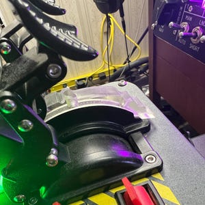 Könnte beinhalten: Nahaufnahme eines schwarzen und grauen Schubhebelquadranten eines Flugsimulators. Der Gashebel verfügt über einen transparenten Kunststoffschutz, rote Schalter und eine Reihe von Kippschaltern. Die Basis hat gelbe und schwarze Gefahrenstreifen.