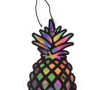 May include: A colorful pineapple-shaped air freshener with a black string for hanging. The pineapple design features a rainbow-colored top and a body with a diamond pattern in shades of green, purple, and yellow. The air freshener is on a white background.