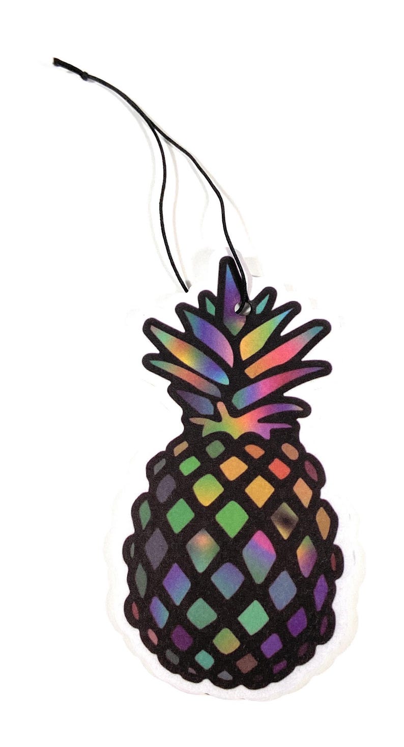 May include: A colorful pineapple-shaped air freshener with a black string for hanging. The pineapple design features a rainbow-colored top and a body with a diamond pattern in shades of green, purple, and yellow. The air freshener is on a white background.