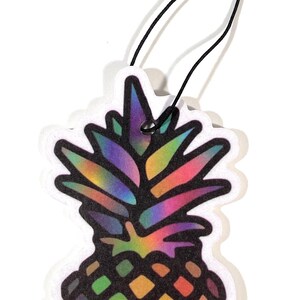 May include: A colorful pineapple-shaped air freshener with a black string for hanging. The pineapple design features a rainbow gradient on the top and a diamond pattern in shades of green, purple, and black.