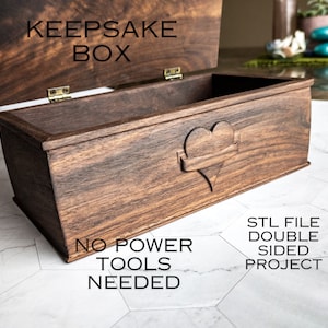 May include: A wooden keepsake box with a heart carved into the lid. The box is open and the inside is visible. The text "KEEPSAKE BOX" is on the lid. The text "NO POWER TOOLS NEEDED" is on the bottom of the box. The text "STL FILE DOUBLE SIDED PROJECT" is on the right side of the box.