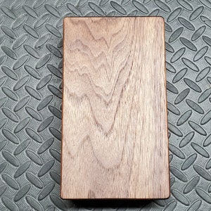 May include: A rectangular wooden board with a natural wood grain pattern. The board has a smooth, polished surface and is a rich brown color.