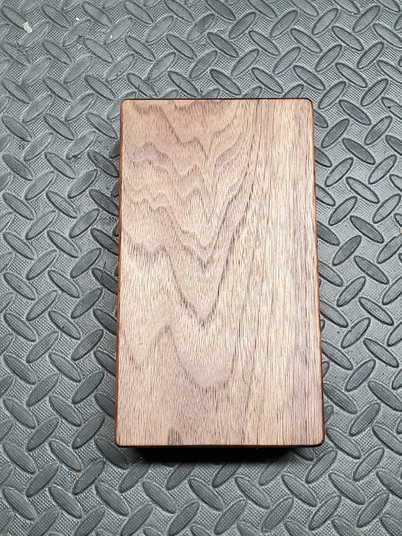 May include: A rectangular wooden board with a natural wood grain pattern. The board has a smooth, polished surface and is a rich brown color.