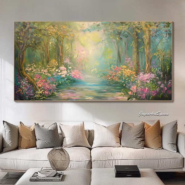 May include: A large, rectangular oil painting depicts a serene forest scene. The artwork features a path of water winding through trees and colorful flowers in shades of pink, yellow, and green. The painting is framed in gold and hangs above a white sofa.