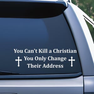 May include: White vinyl decal applied to a car window. The decal features the text "You Can't Kill a Christian, You Only Change Their Address" with a cross symbol on each side of the text.