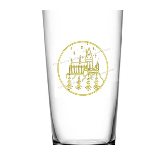 May include: A clear glass with a gold outline of Hogwarts castle and stars inside a circle. The glass is perfect for holding beverages.
