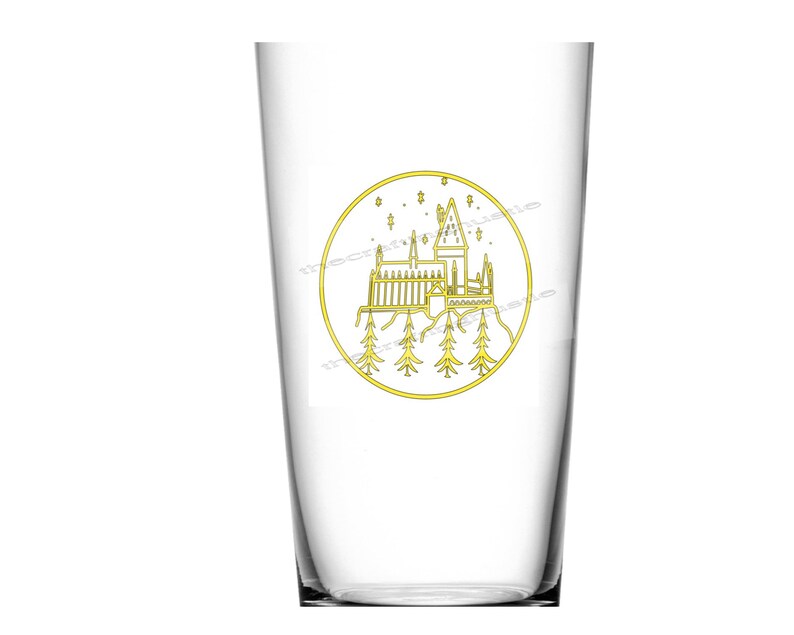 May include: A clear glass with a gold outline of Hogwarts castle and stars inside a circle. The glass is perfect for holding beverages.
