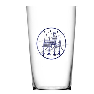 May include: A clear glass cup with a blue and white illustration of Hogwarts castle in a circle. The castle is surrounded by trees and stars.