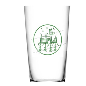 May include: A clear glass cup with a green outline of Hogwarts castle and stars in a circle on the front.