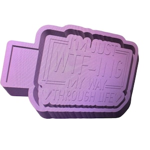 May include: A light purple rectangular object with the text "I'M JUST WTF-ING MY WAY THROUGH LIFE" in a bold, sans-serif font. The object has a raised border and a small rectangular extension on the left side.