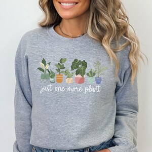 May include: Gray sweatshirt with a graphic of potted plants and the text "just one more plant".