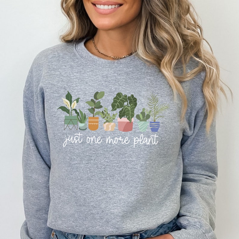 May include: Gray sweatshirt with a graphic of potted plants and the text "just one more plant".