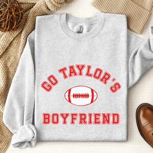 May include: Gray sweatshirt with red text that says "Go Taylor's Boyfriend" with a football graphic.