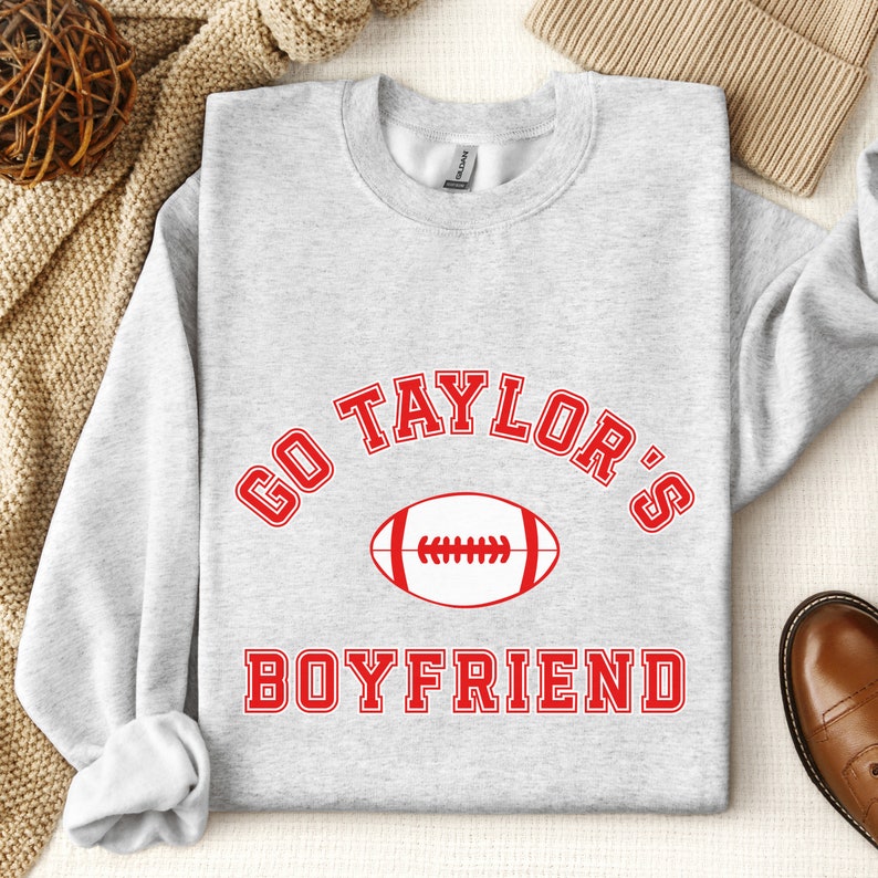 May include: Gray sweatshirt with red text that says "Go Taylor's Boyfriend" with a football graphic.