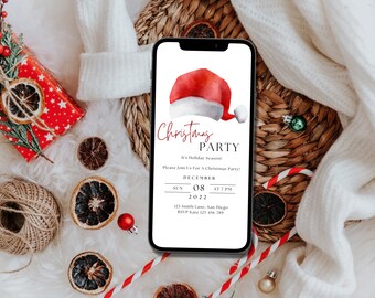 May include: A smartphone displays a Christmas party invitation with a Santa hat graphic. The invitation text reads "Christmas Party" and includes date, time, and RSVP information. The image is surrounded by festive decorations, including a wrapped gift, dried orange slices, and ornaments.