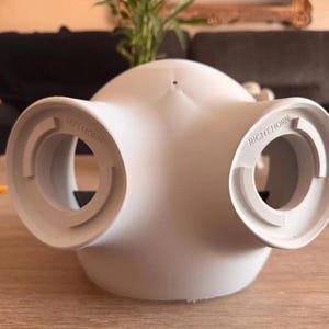 May include: A matte white, dome-shaped object with two circular openings on the sides. The left opening is embossed with the text LEFT HORN, and the right opening is embossed with the text RIGHT HORN. The object has a smooth, curved surface.