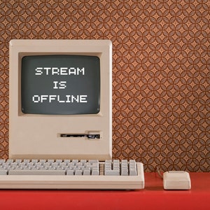 Puede incluir: Un ordenador de estilo vintage con un monitor que muestra el texto "STREAM IS OFFLINE" sobre un fondo de patrón marrón.