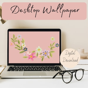 May include: A laptop screen shows a floral desktop wallpaper with a pink backdrop and watercolour flowers. The words "Desktop Wallpaper" and "Digital Download" are visible. Black glasses sit on the table in front of the laptop.