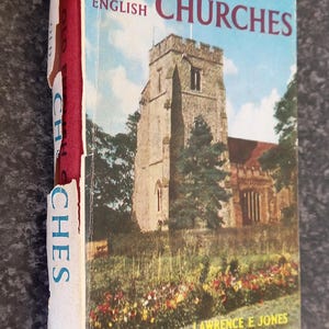 Könnte beinhalten: Das Beobachterbuch alter englischer Kirchen, ein Vintage-Buch mit rotem Einband und einem Foto einer Steinkirche mit einem hohen Turm und einem grünen Rasen mit Blumen im Vordergrund. Der Titel des Buches ist in blauem und weißem Text gedruckt.