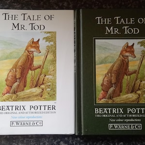 Puede incluir: Dos ejemplares de "The Tale of Mr. Tod" de Beatrix Potter. Uno tiene una cubierta blanca, el otro una cubierta verde oscuro. Ambos presentan una ilustración de un zorro con abrigo marrón y bastón. El texto "BEATRIX POTTER" es visible.