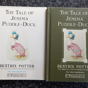 Op de afbeelding: Twee exemplaren van "The Tale of Jemima Puddle-Duck" van Beatrix Potter. Eén boek heeft een witte kaft, de andere is groen. Beide tonen een illustratie van een eend met een muts en jurk. De tekst bevat "New colour reproductions" en de naam van de uitgever.