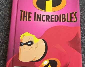 May include: A hardcover book titled "The Incredibles" featuring a cartoon illustration of a superhero. The cover is predominantly pink and red, with the Disney and Pixar logos at the top. The Ladybird logo is at the bottom.