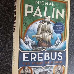 May include: Book cover for "Erebus: The Story of a Ship" by Michael Palin. The cover features a detailed illustration of a ship sailing through icy waters, with a quote from Bill Bryson on the right side.