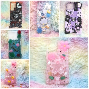 Könnte beinhalten: Eine Sammlung von sechs dekorativen Handyhüllen mit verschiedenen Motiven, darunter eine schwarze Katze, Pinguine, violette Zeichentrickfiguren, ein Koiteich und rosa Kirschblüten-Designs, alle verziert mit kleinen Harzanhängern und Applikationen.