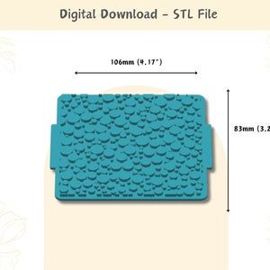 Puede incluir: Una estera de silicona texturizada azul turquesa con un patrón de círculos en relieve. La estera mide 106 mm por 83 mm.