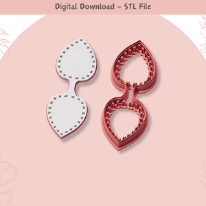 Op de afbeelding: Twee 3D-geprinte koekjesvormen, een wit en een rood, in de vorm van een paar bladeren. De witte vorm heeft een gestikt ontwerp rond de randen. Digitale download - STL-bestand