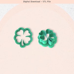 May include: Two green plastic four-leaf clover cookie cutters. One cutter is a single piece, the other is a multi-piece cutter.