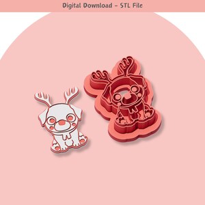 May include: Two 3D printed cookie cutters in the shape of a dog wearing a reindeer antler headband. The cutter on the left is white and the cutter on the right is red.