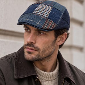 May include: A flat cap featuring a patchwork design of blue, navy, and brown wool fabrics. The cap displays a mix of herringbone, houndstooth, and plaid patterns across its panels, with a structured brim and a rounded, stitched crown.