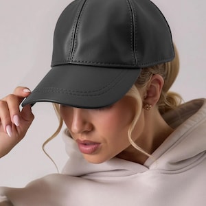 May include: A black baseball cap made of a smooth material. The cap has a curved brim and a structured crown with visible stitching details. The cap is a solid color and appears to be made of leather or a leather-like material.