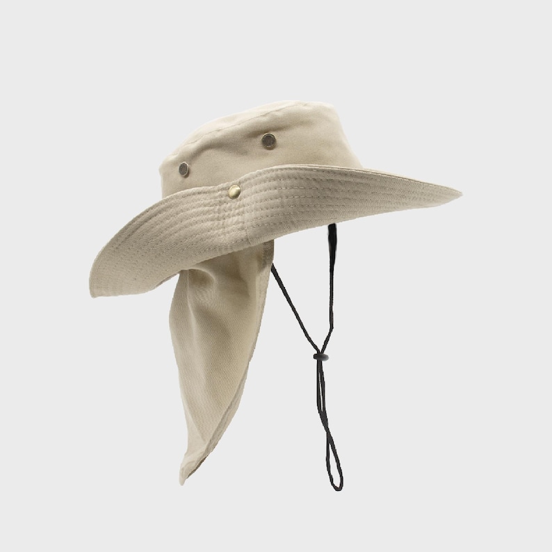 May include: A beige sun hat with a wide brim and a neck flap. The hat has a drawstring and metal rivets. The hat is designed to provide sun protection. The hat is made of a durable fabric.