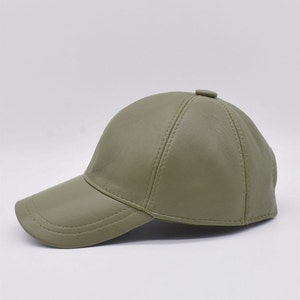 May include: Olive green baseball cap with a curved brim. The cap is made of a smooth material and features a button on top. The cap has a classic six-panel design with stitched seams.