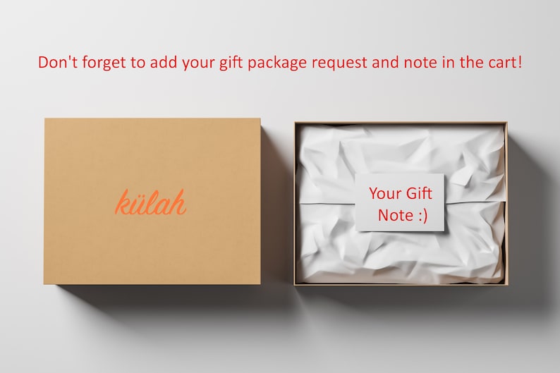 May include: A brown cardboard box with the word "k&uuml;lah" printed on it. The box is open and a white tissue paper-filled box is inside. The tissue paper is crumpled and a white card with the text "Your Gift Note :)" is on top of the tissue paper.