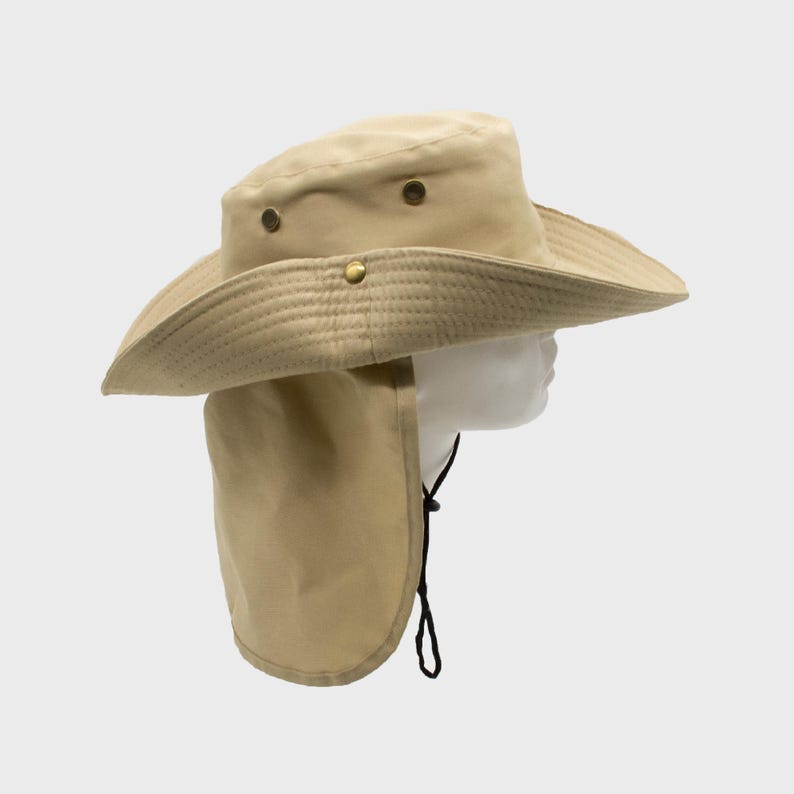 May include: A tan-colored sun hat with a wide brim and a neck flap. The hat has a structured crown with brass-colored rivets and a chin strap. The hat is designed to provide sun protection.