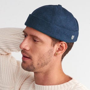 May include: A dark blue wool watch cap with a small logo on the side.