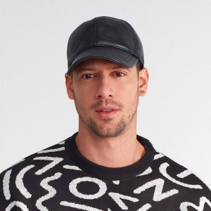 May include: A black leather baseball cap with a curved brim. The cap has a stitched seam down the center of the crown.