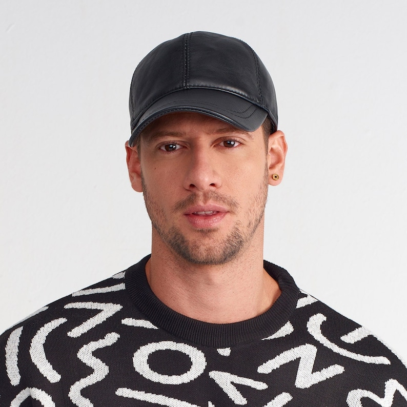 May include: A black leather baseball cap with a curved brim. The cap has a stitched seam down the center of the crown.