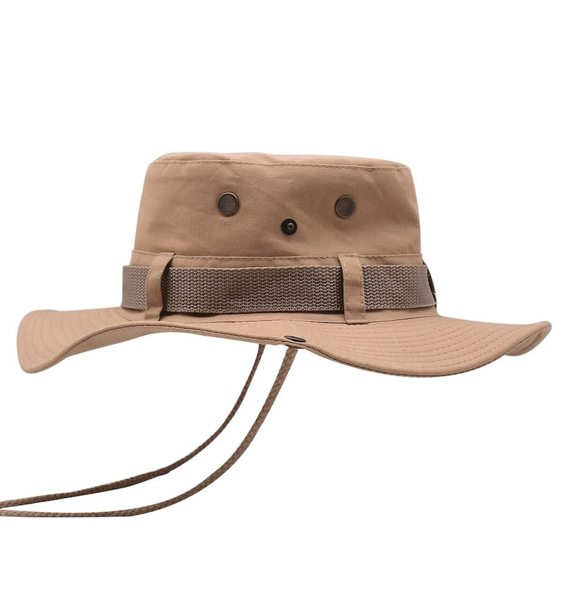 May include: A tan canvas bucket hat with a brown adjustable strap and a chin strap. The hat has two metal eyelets on the crown.