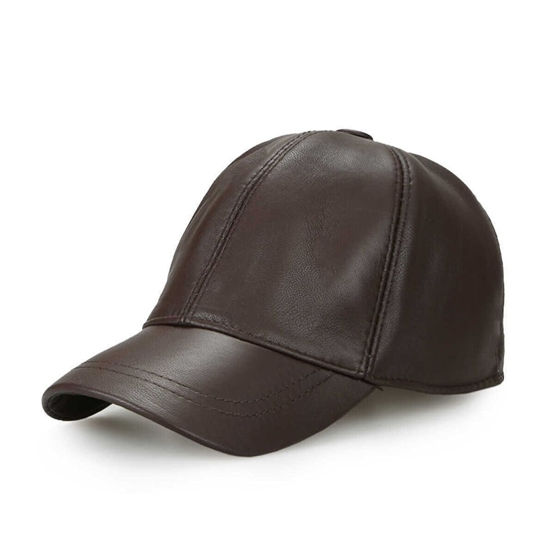 May include: A brown leather baseball cap with a curved brim. The cap has a classic six-panel design with stitched seams and a button on top. The leather has a smooth, glossy finish.