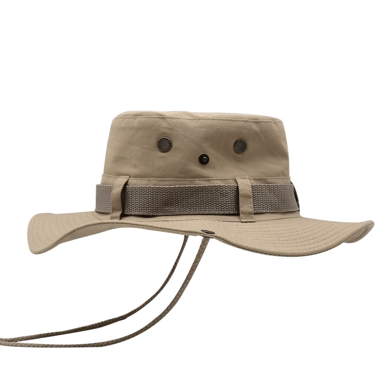 May include: A khaki-colored, wide-brimmed sun hat with a brown strap and a chin strap. The hat has a button on the top and two eyelets on the crown.