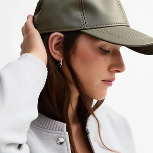 May include: Olive green baseball cap with a curved brim and stitched detailing. The cap is made of a smooth material and has a classic design. The cap is a stylish accessory for casual wear.