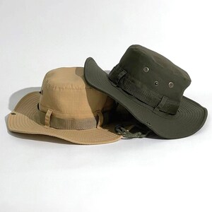 May include: Two sun hats, one in khaki and one in olive green, with wide brims and adjustable straps. Both hats have a simple design with a flat crown.