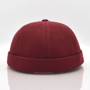 May include: A burgundy cotton beanie with a wide brim.